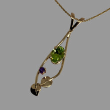 Load image into Gallery viewer, Slender 14K gold pendant with an oval peridot in the center hugged by a pair of leaves and vines and accented with a smaller amethyst.