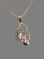 sparkling peachy/pink sapphire with a row of diamonds in a 14K rose gold setting