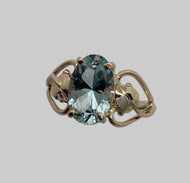 fancy cut oval Aquamarine  in 14K gold ring that has a leaf and a heart on sides of gem