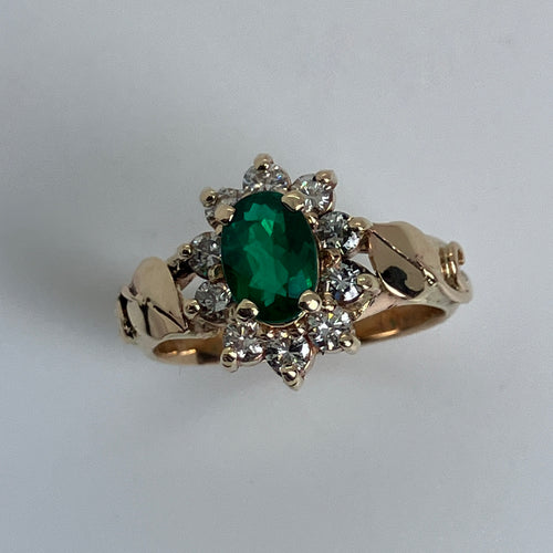 perfect color emerald in a halo of diamonds with precious leaves on the side ring