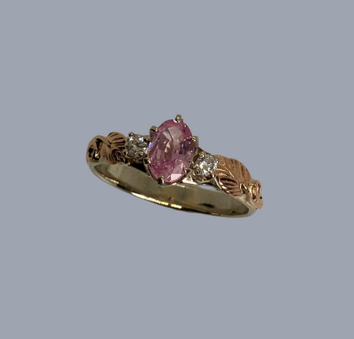 peachy-pink gorgeous oval padparadscha sapphire with 2 diamonds in a rose and white gold band with handmade leaves