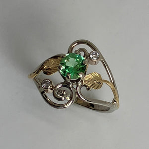 white gold ring with a  round lime green gemstone and 18K yellow gold leaf design