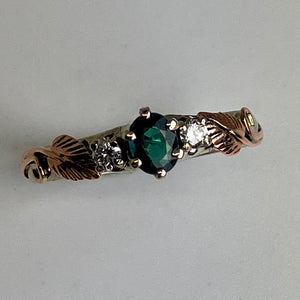 white gold ring with a blue/green garnet, 2 diamonds and rose gold leaves