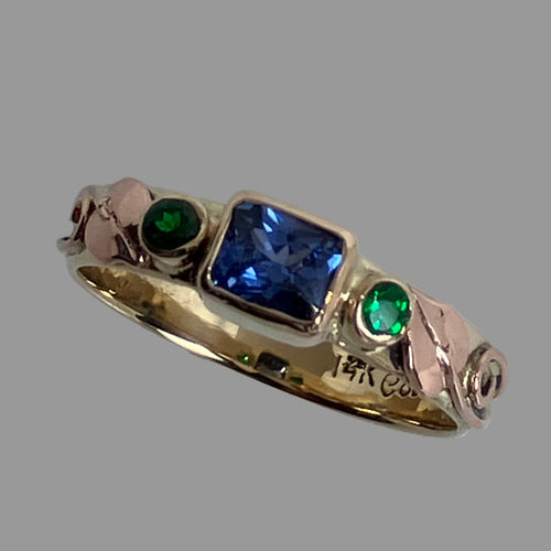 Emerald cut blue sappphire and 2 round tsavorite garnets, leaves and vines ring