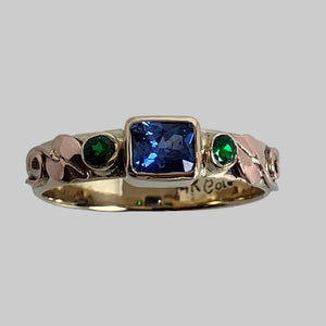 14K yellow band with rose gold leaves and swirls, blue emerald cut saphhire and round tsavorite garnets