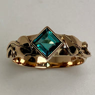 yellow gold ring with a blue square gemstone, leaves and vines