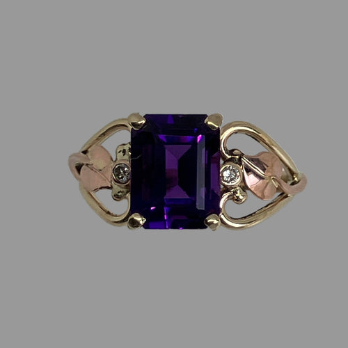 emerald cut purple amethyst set in 14K yellow gold open work ring with  rose gold leaves and 2 bezel set diamonds