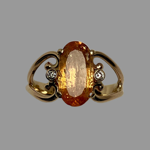 Large oval amber colored Topaz and 2 smaller diamonds in an open worked 14K gold band