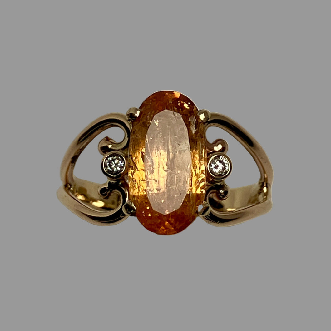 Large oval amber colored Topaz and 2 smaller diamonds in an open worked 14K gold band