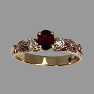 Gold ring with a deep red garnet and diamonds with leaves and vines