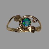 Gold ring with a round blue/green opal in a bezel with leaves and a diamond.
