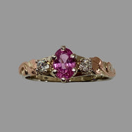 white and rose gold ring with an oval pink sapphire and 2 diamonds, with leaves and vines