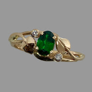 Oval forest green garnet with 2 small diamonds and two leaves and vines