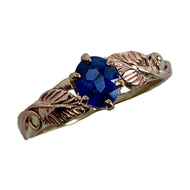 14K yellow gold ring with a fine bright blue sapphire on with 2 rose gold leaves and vines