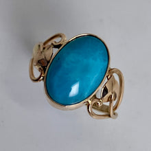 Load image into Gallery viewer, A  large oval turquoise Larimar  cabochon gemstone in a 14K gold ring with a leaf inside an open  heart on each side of the handmade shank
