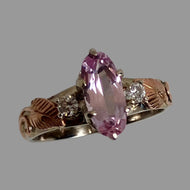 A  14K white and rose gold  ring featuring a large marquise-cut pink Topaz in the center and a diamond on either side,