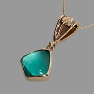14K yellow gold pendant with freeform green Peruvian Opal in a bezel setting, suspended from a fancy bail with a leaf and vine motif, on an 18