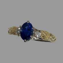 Load image into Gallery viewer, 14K white and  18K yellow gold ring featuring an oval-cut deep blue sapphire center stone, accented by a small round diamond on each side, leaf and vne motif.
