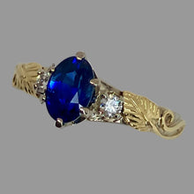 Load image into Gallery viewer, 14K white and 18K yellow gold ring with an oval deep blue Ceylon sapphire in the center, accented by a pair of small round natral diamonds and a pair of leaves and vines
