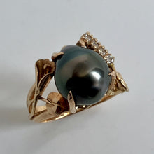 Load image into Gallery viewer, 14K yellow gold ring featuring a large, droplette shaped, lusterous black pearl as the center, accented by 4 diamonds  on the upper right and a leafand handmade cala lilly  details on the side..
