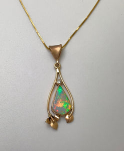 A free form solid Australian Opal with a mosaic of colors surrounded by a handmade 14Kgold lily and leaf.